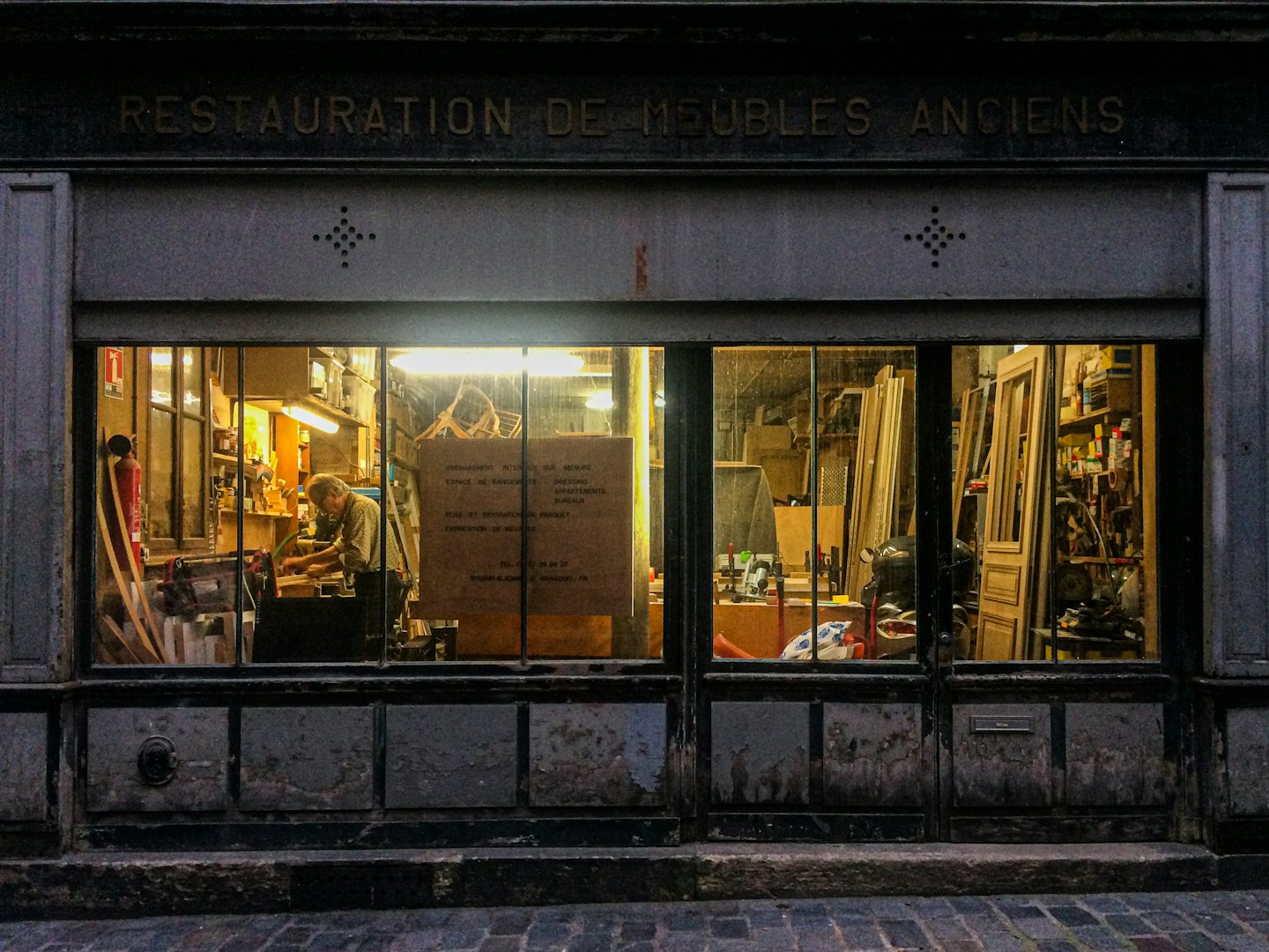 Handwerker arbeitet an Möbeln in einer unordentlichen Restaurationswerkstatt.
